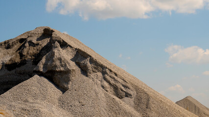 Mountain of rubble against the blue sky with clouds on a sunny day