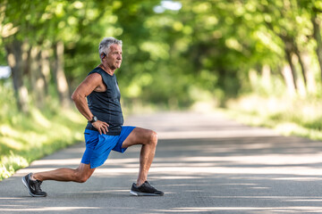 Aged man stretches legs outdoors surrounded by trees before his workout