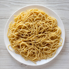 Homemade Cacio E Pepe Pasta with Pecorino Romano and Pepper on a white plate on a white wooden background, top view. From above, overhead, flat lay.