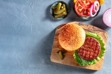 Burger ingredients. Hamburger patty, sesame bun,m tomato, onion and pickles, shot from the top on a...
