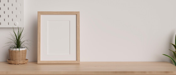 Mock-up wooden frame with copy space for product display on wooden table decorated with plants and white wallpaper