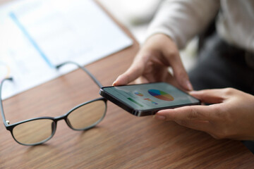 Fototapeta premium Close up of female looking on financial chart on her smartphone