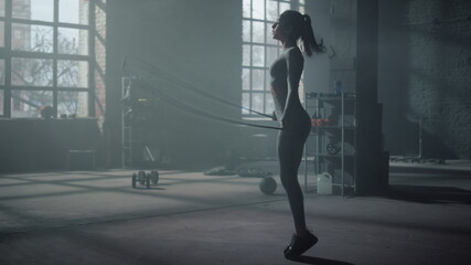 Fototapeta na wymiar Sportswoman jumping on skipping rope in gym. Fit woman doing cardio workout