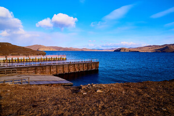 An old wooden pier on a sunny day with blue water and sky