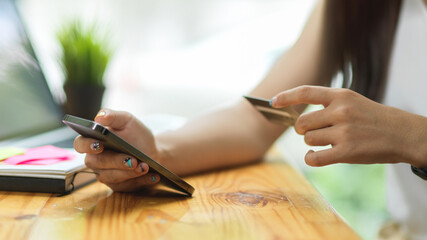 Close up female paying via smartphone with credit card, Cashless payments