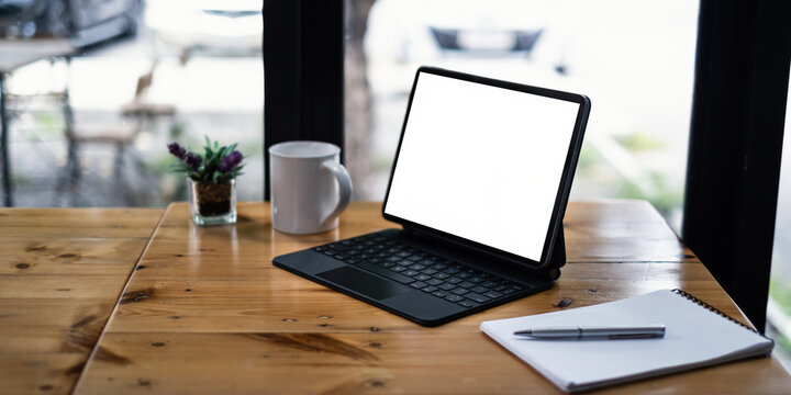 Mockup image of a black tablet with white blank screen on wooden desk.