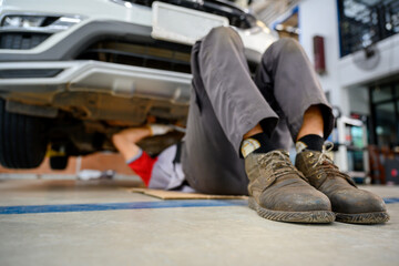 auto repair service sleep under the car Check the car suspension with rebar during balance adjustment. Align the car suspension at the auto repair station.