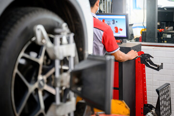 Auto service mechanic installing wheel alignment sensor on tire during vehicle suspension alignment...