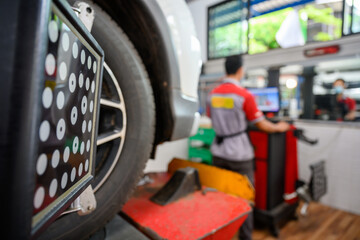 Auto service mechanic installing wheel alignment sensor on tire during vehicle suspension alignment...