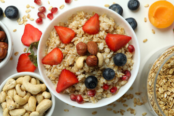 Bowl of oatmeal and ingredients for cooking on white background
