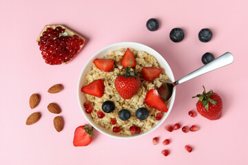 Concept of tasty eating with oatmeal on pink background