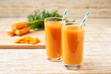 Fresh carrot juice in glasses on a  white wooden table, selective focus.
