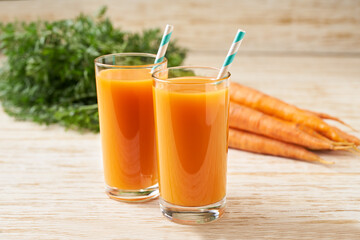 Fresh carrot juice in glasses on a  white wooden table, selective focus.