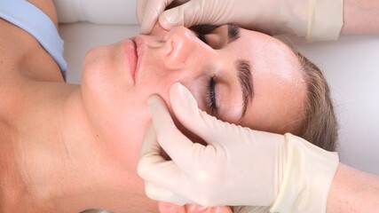 Beautiful woman in salon having facial massage.