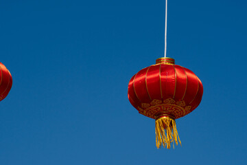 Day, a red Chinese traditional beautiful flashlight is hanging against the background of a clear blue sky