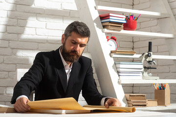 Portrait of male teacher working at desk in class. Tutor, professor, mentor man at desk. Studying,...