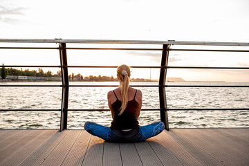 Young woman doing sports exercises at dawn near the ocean.	