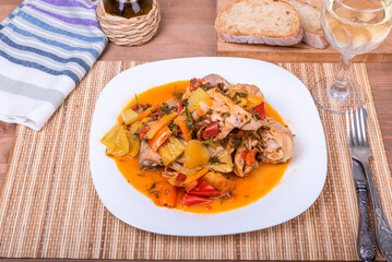 Chicken stew with vegetables - serving on a plate with wine and bread on the table
