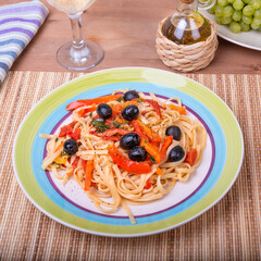 Italian linguini pasta with pepper and, tomatoes and olives - portion on a plate