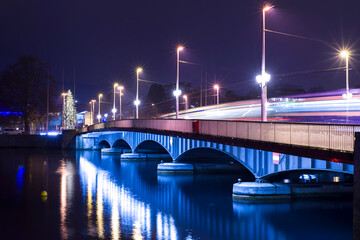 Fototapeta na wymiar Tram Crossing a Bridge over Limmat River at Night in Long Exposure in Zurich, Switzerland.