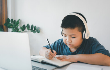 Asian boy learning online education at home with digital tablet and doing school homework.