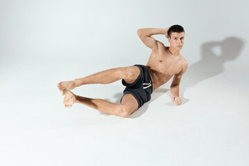Fototapeta premium sports guy doing exercises in shorts in a bright room front view