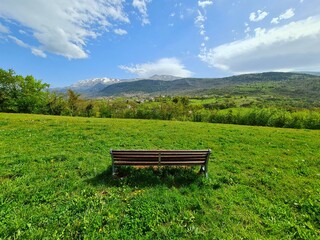 Wooden Bench in a Greenfield with a View of the Mountains, Parco del Sole, L'Aquila, Italy