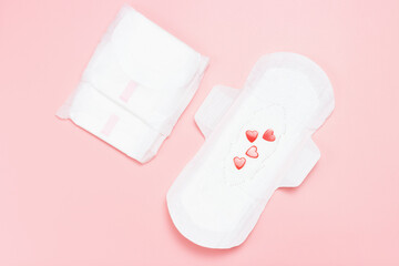 White feminine pads with red hearts on pink background.