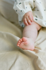 Close-up of the legs and arms of a little girl 8 months old on a beige background. Cozy. Home.