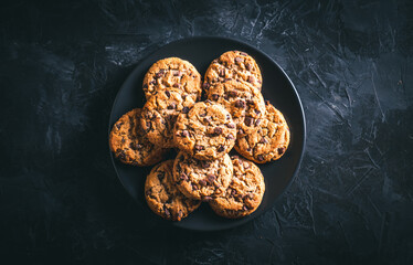 Homemade chocolate chip cookies on a black plate on a dark table. Ready to eat.