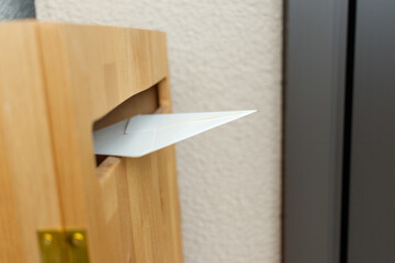 玄関横の木製のポストに投函された手紙
