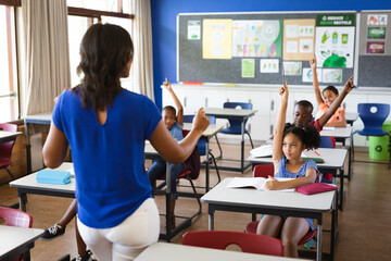Rear view of african american female teacher teaching students in the class at elementary school