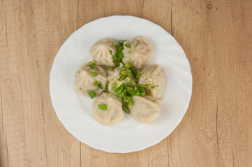 khinkali on a white plate with green onions