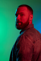 Portrait of young handsome smiling caucasian guy isolated on green background in blue neon light.