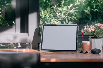 Mockup blank tablet on wooden counter table in cafe.