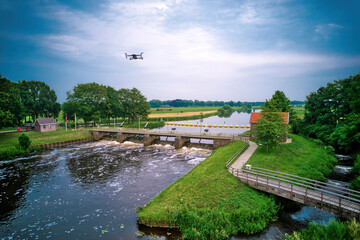 An aerial view with drone in the background above a weir in the river Vecht in the Netherlands. Downstream, Sluiswachtershuis next to the bridge. Fish pass, fish ladder. Overijssel Vecht