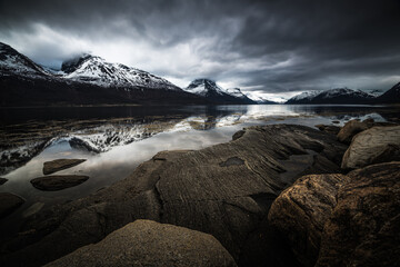 Scenic fjord landscape with snow and refection on a calm cold cloudy winter day in northern norway near Tromso
