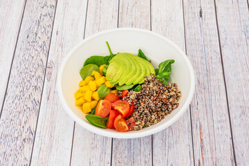 vegetable salad with cooked white and red quinoa. Chopped cherry tomatoes, Mexican ripe avocado, Asian chopped mango and Spanish lamb's lettuce.