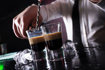 Barman preparing cocktail shots at the bar counter. Barman mixing drinks at the night club