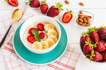 Breakfast. Oatmeal with bananas, strawberries, nuts on the wooden bakground. Healthy breakfast. Close-up. Top view