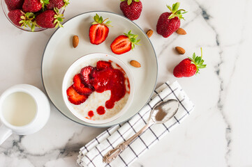 Oatmeal Porridge with Strawberries and almonds in white bowl. Healthy Breakfast with Oatmeal and Fresh Organic Berries.