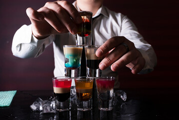 Barman preparing cocktail shots at the bar counter. Barman mixing drinks at the night club