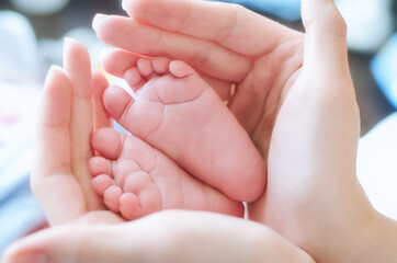 The baby's small legs in his mother's hands