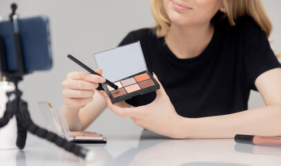 Beauty blogger young woman records video tutorial of course on makeup for skin on phone