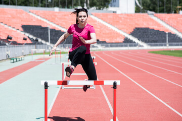 Obraz premium Woman athlete jumping over an obstacle. Running with hurdles. Active lifestyle