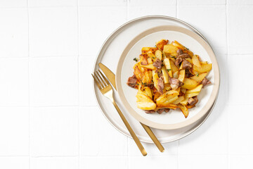 Fried potatoes with turkey meat and thyme in a plate on a white culinary background top view