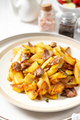 Fried potatoes with turkey meat and thyme in a plate on a white culinary background closeup