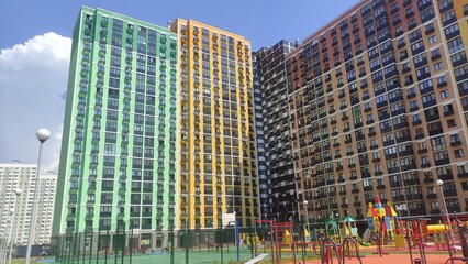 Multi-colored multi-storey new buildings with apartments against the blue sky in summer on a sunny bright day with beautiful bright facades with windows and glass