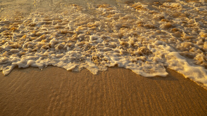 Scenic seascape. Milky foam waves at the beach. Sunset time. Waterscape for background. Selected soft art focus. Sunlight reflection on the water and sand. Balangan beach, Bali, Indonesia