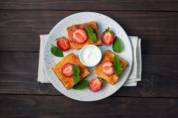 Cottage cheese casserole with strawberries and mint. Delicious homemade dessert made of curd and fresh berries with cream. dark wooden background, copy space.